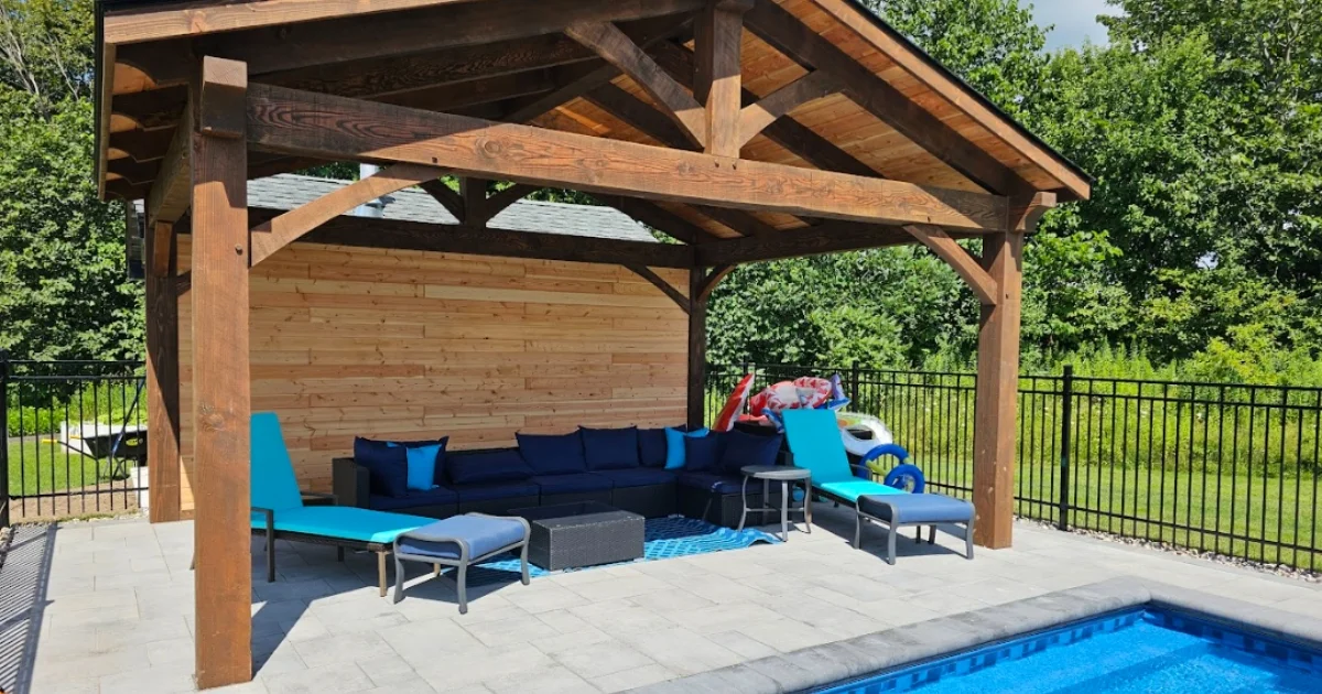 Poolside timber pavilion with wooden ceiling, furnished with lounge chairs and a sofa